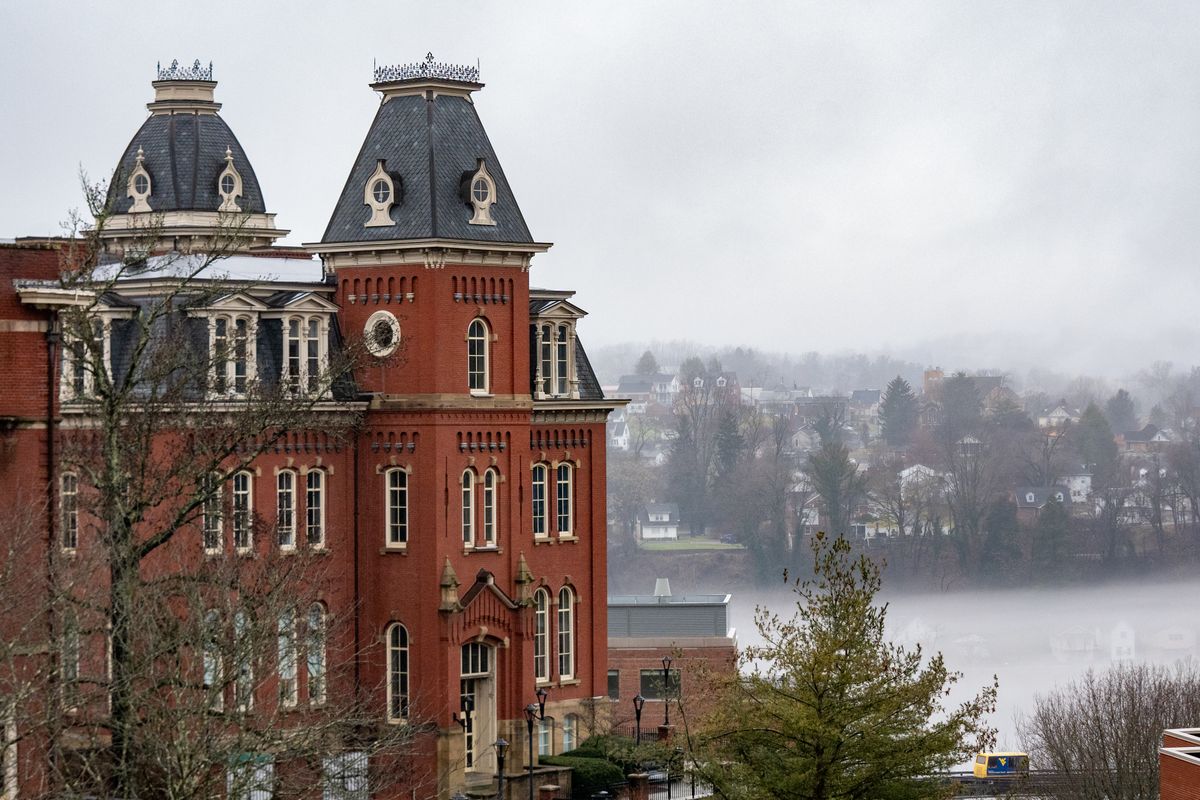 The side of Woodburn Hall is shown with fog over the river in the background on a gray day.