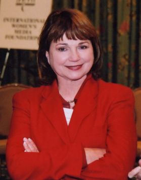 A woman wearing a red jacket, arms folded