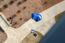 A box with a blue parachute containing a pumpkin is shown in free fall at the Engineering Sciences Building.