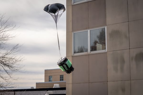 A student's engineering design is being tested by dropping. Their concept is a trash can with a parachute.