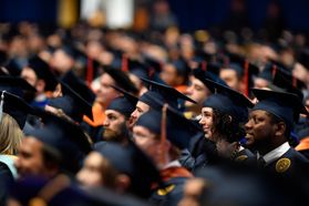 Dozens of graduates wear blue mortarboards at the Coliseum.