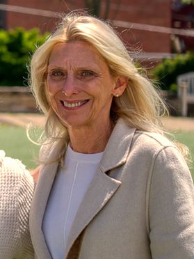 smiling woman, long blond hair, white shirt, tan jacket