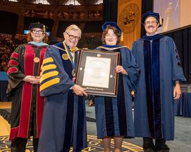 President Gordon Gee, College of Applied Human Sciences Dean Autumn Cyprès and Faculty Senate Chair Scott Wayne present an honorary degree to Carolyn Long. All are in academic regalia.