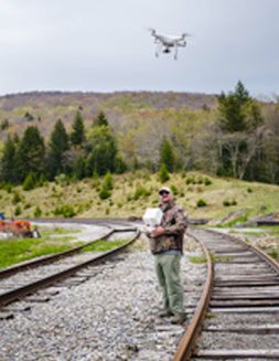 Paul Kinder operates a drone along railroad tracks.
