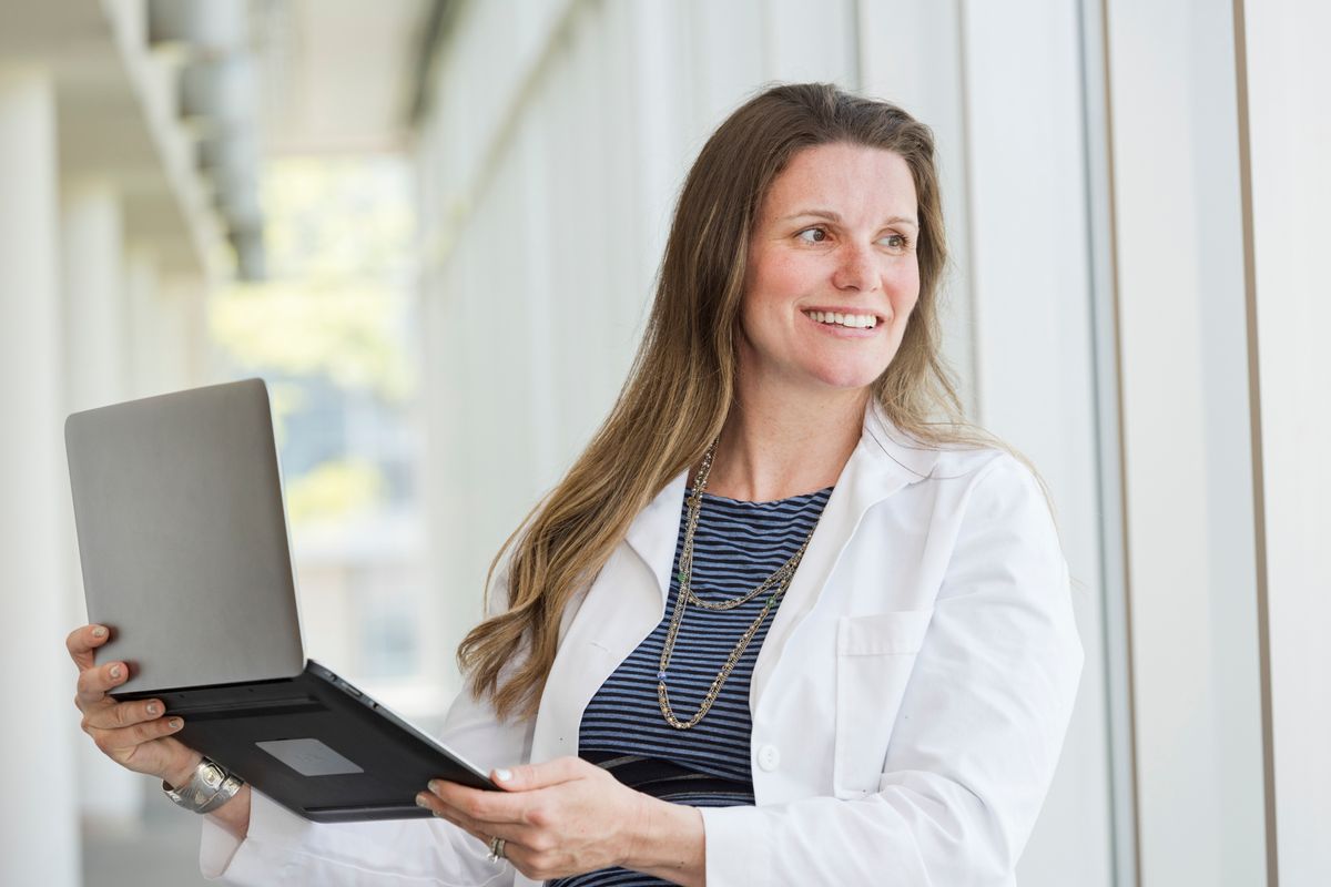 photo of smiling woman in white coat holding a tablet