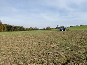 An open field with farm equipment and a tree line in the distance that's being used in a research study about manure in organic farming. 