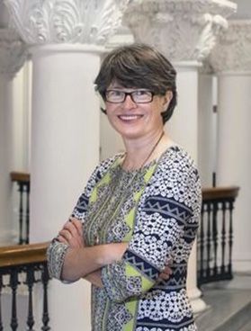 Headshot of associate vice president for research development at WVU, Sheena Murphy. She is pictured inside with ornate white columns in the background. She is wearing a vibrantly patterned dress, has short brown hair and wears square framed glasses. 