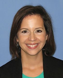 Headshot of WVU School of Dentistry professor Dr. Gina Graziani. She is pictured against a light blue background and is wearing a black jacket over a green shirt. She has shoulder-length brown hair. 