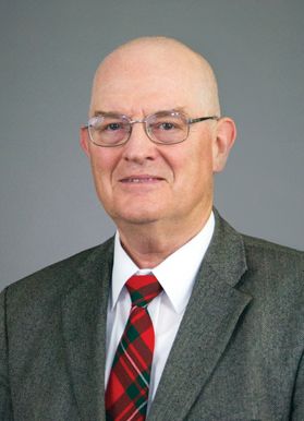 Man in a suit coat with a red plaid tie and glasses