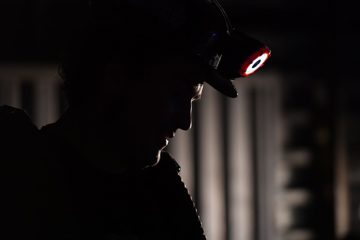 person in shadows wearing miner's hat with light