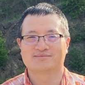 Headshot of WVU researcher Kesheng Wang. He is pictured outside with trees in the background. he is wearing an orange plaid shirt, has dark hair cut short and is wearing glasses. 