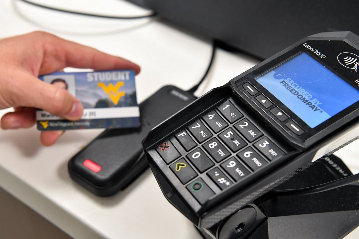 hand holds an id card next to a swipe machine
