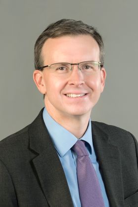 smiling white man in glasses on grey background