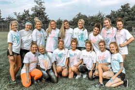 group of women pose on a field in t-shirts