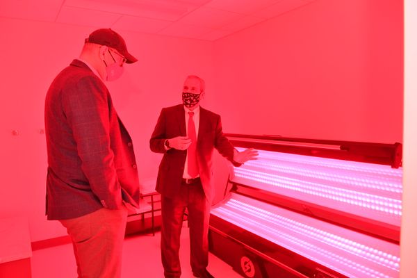 two men look at tubes of light, red cast over photo