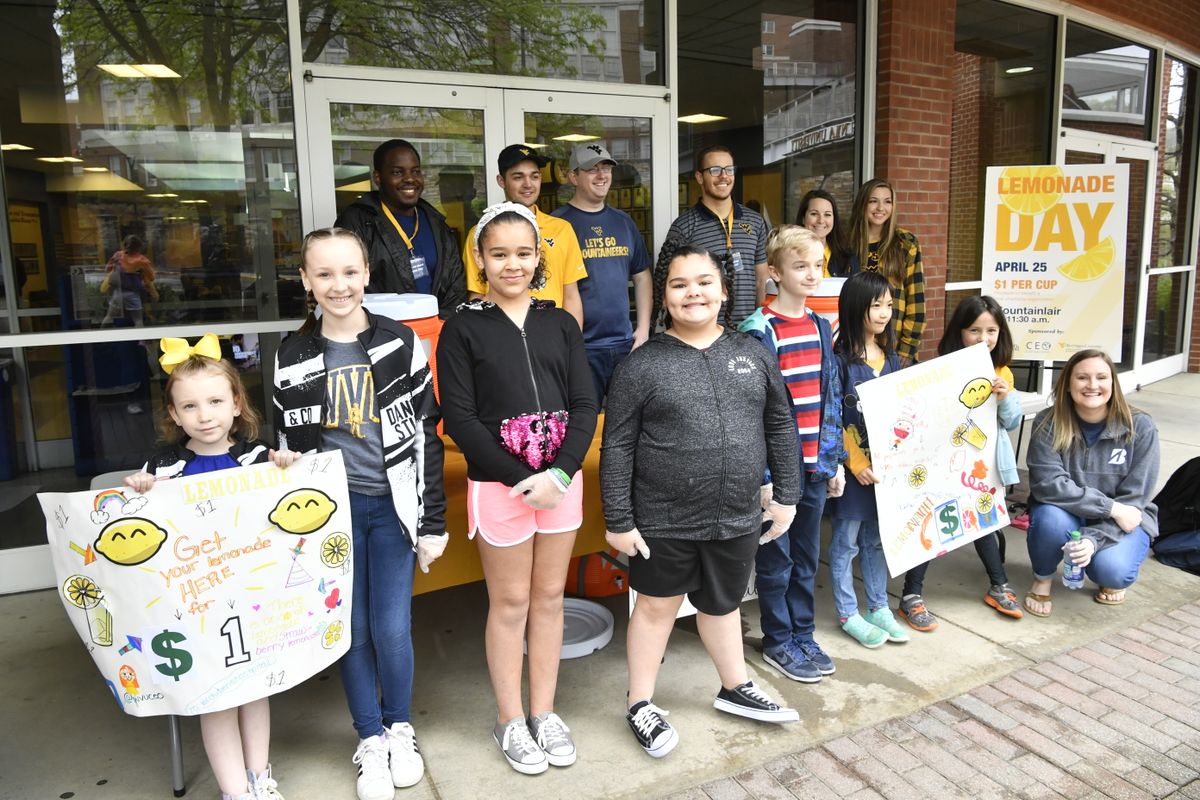 group of children stand with posters in front of young adults