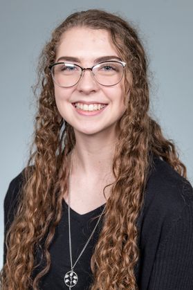 Woman with curly brown hair and glasses