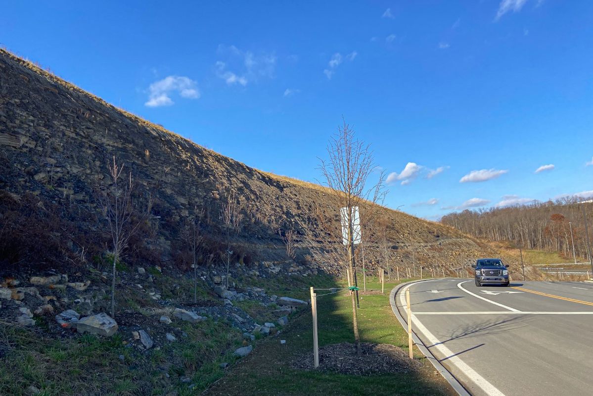 truck travels down exit ramp beside a rocky hillside