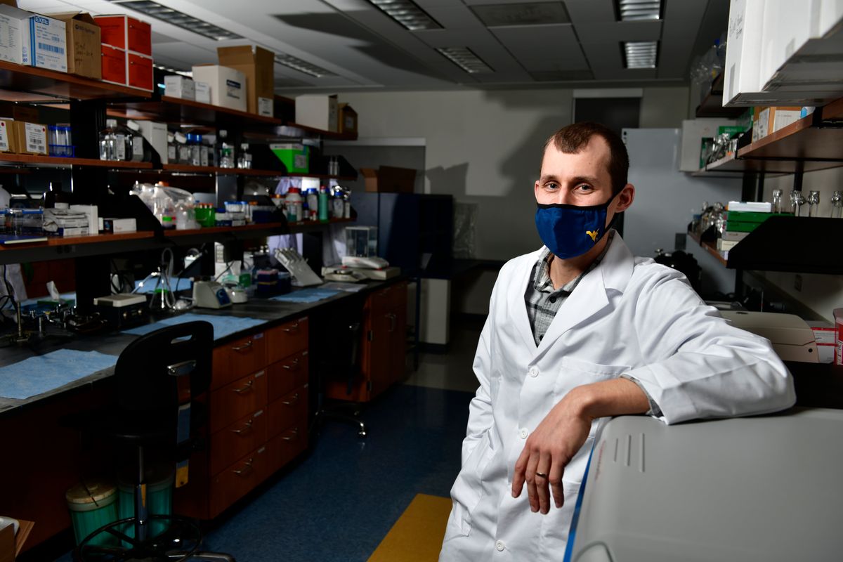 man in whitecoat stands in lab storage room