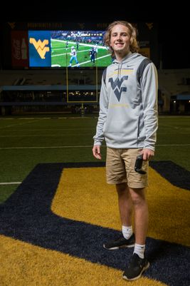 young man, long hair, sweatshirt, shorts on athletic field