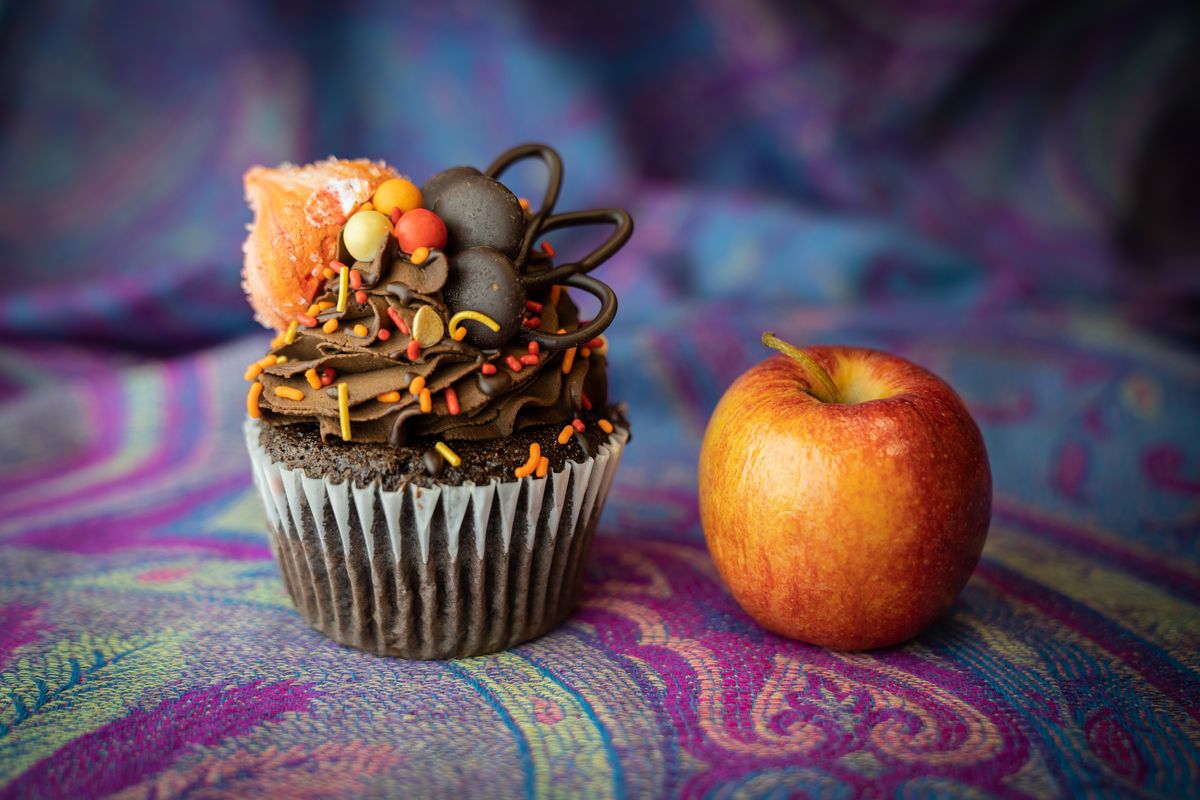 a cupcake and an apple sit on woven cloth