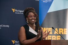 smiling woman in front of WVU backdrop, clapping