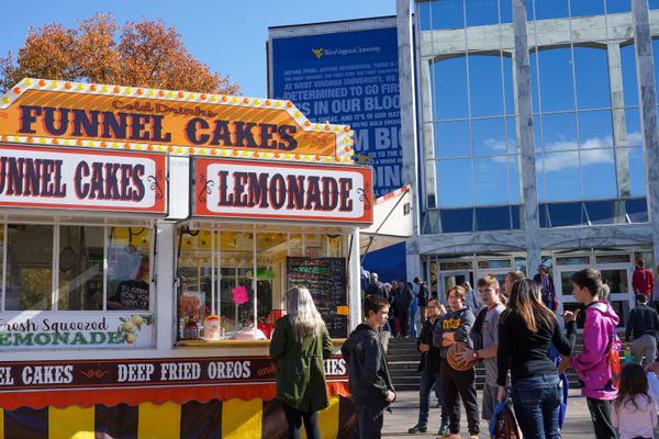 Students gather in front of the Mountainlair at a food vendor selling funnel cakes, lemonade and other treats for Mountaineer Week.