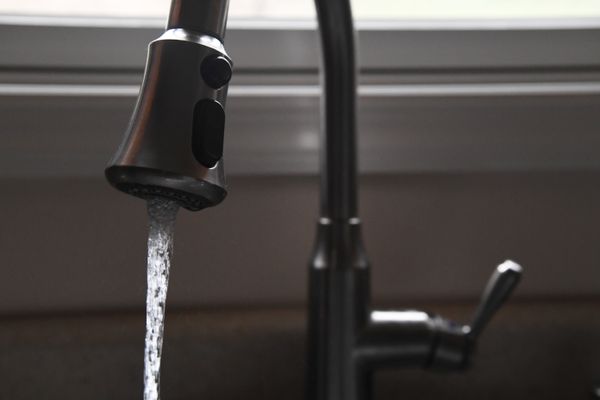 Photograph of a kitchen sink faucet with water running from the tap. 