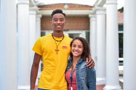 young man, young woman stand outside in walkway with columns on side