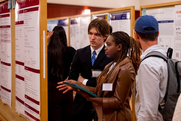 Undergraduate WVU students present research conducted during the summer at the Undergraduate Summer Research Symposium. Two males and one female stand in front of a poster in discussion. 