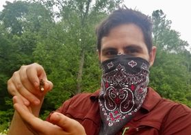 man in mask holds insect