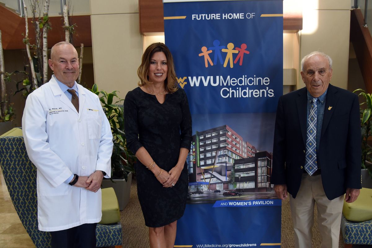 Two men and one woman flank a popup banner that says WVU Medicine Children's