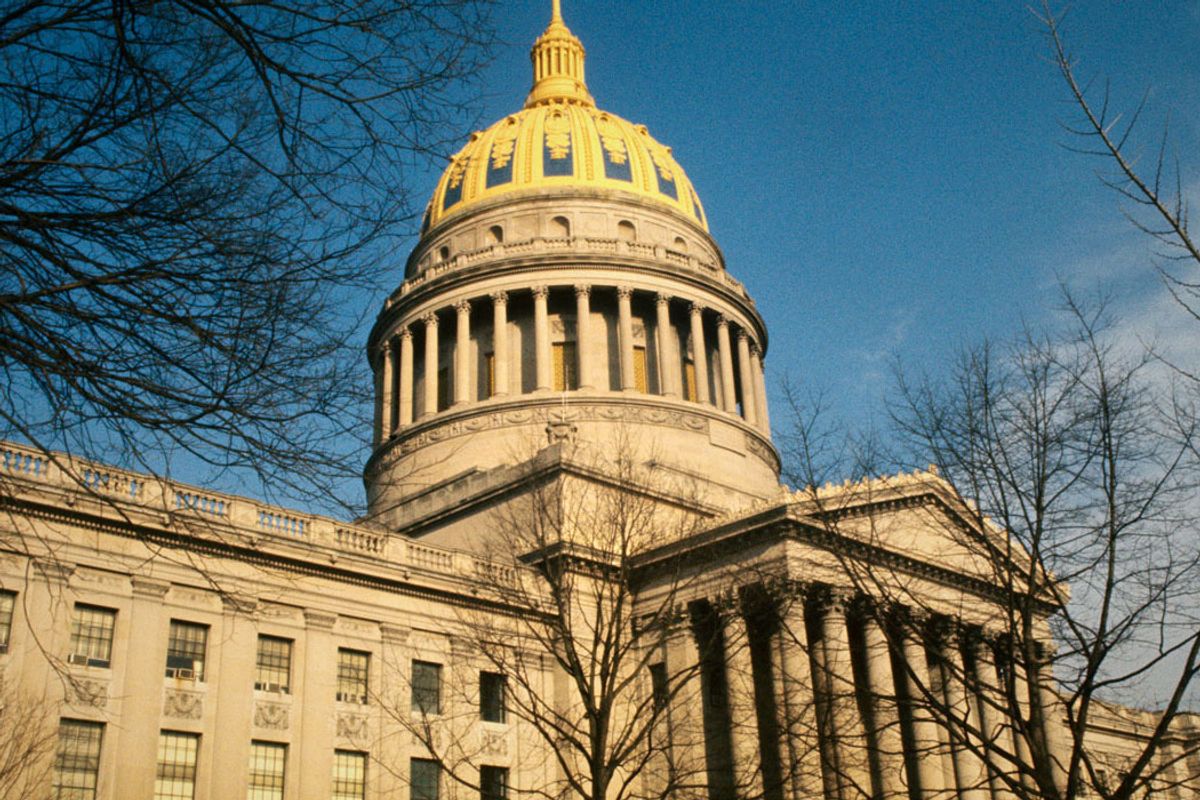 Photo of a capitol dome with gold against a blue, nearly cloudless sky