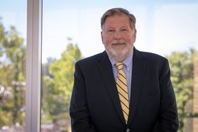 Photo of a bearded man wearing suit jacket and gold striped tie