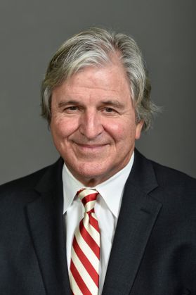 man with grey hair in dark suit and tie