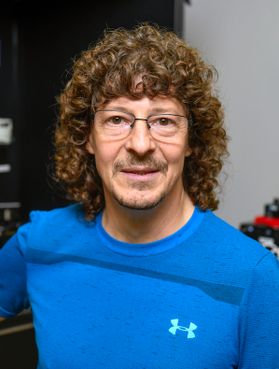 Professor Kevin Daly is pictured here wearing a blue shirt, he has curly hair and wire-rimmed glasses.