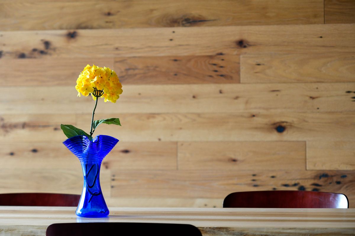 Yellow flower in blue vase sitting on table