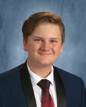 Headshot of WVU Bucklew Scholar WIll Behrens. He is pictured against a blue marbled background wearing a dark colored jacket, white dress shirt and red tie. He has short, light colored hair. 