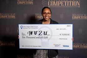 A young woman in glasses holds a big check