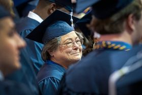 woman smiles in a graduation cap