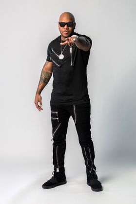 This is a portrait of Flo Rida who is wearing all black and standing in front of a white backdrop.