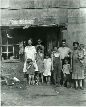 A group of people, including children, stand outside a building