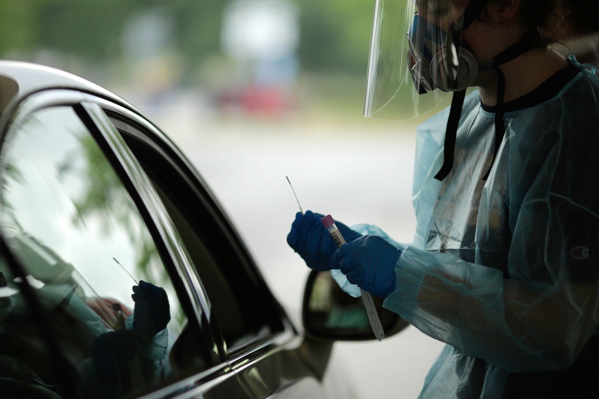 person in PPE at a car window