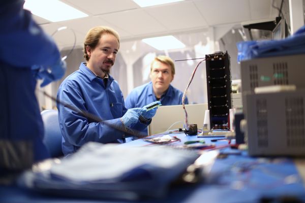 Men dressed in blue work in a lab